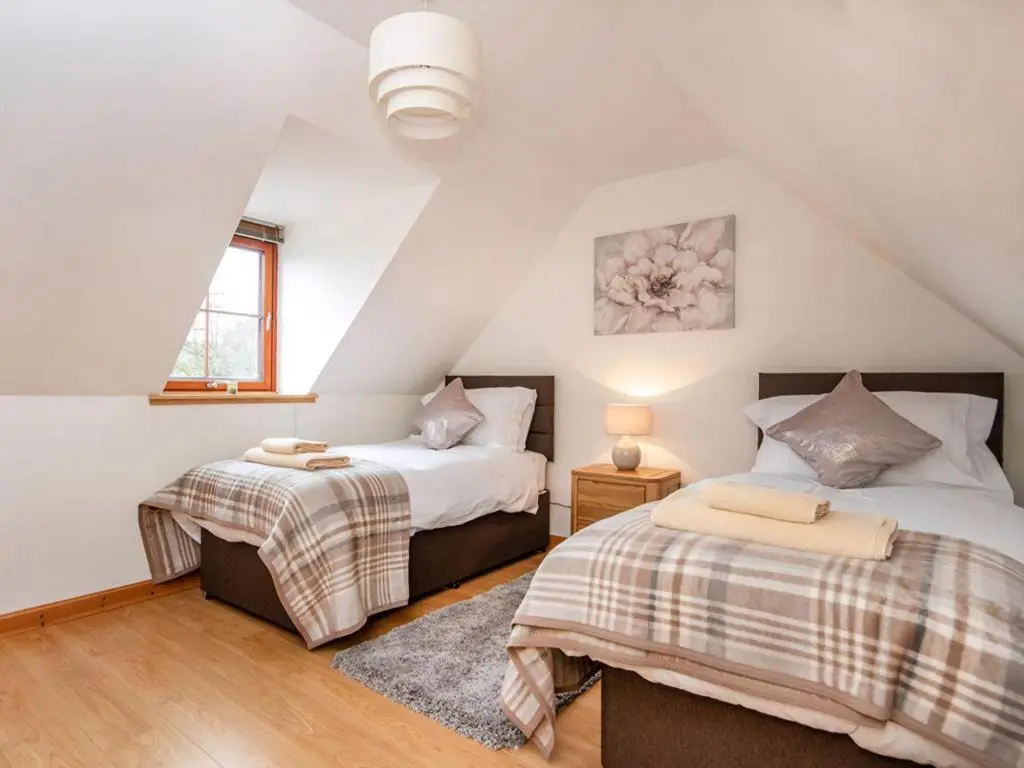 a attic bedroom with two beds and a window at The Hive in Dornoch
