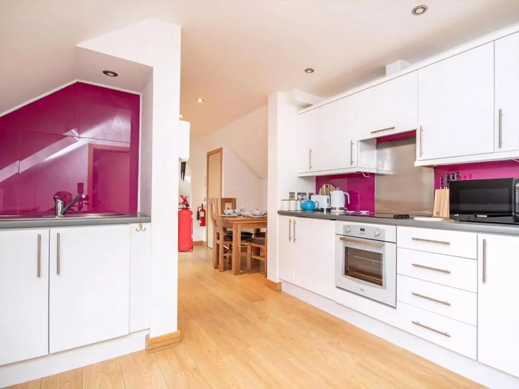 a kitchen with white cabinets and purple accents at The Hive in Dornoch