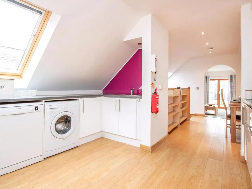 an attic kitchen with a washer and dryer at The Hive in Dornoch