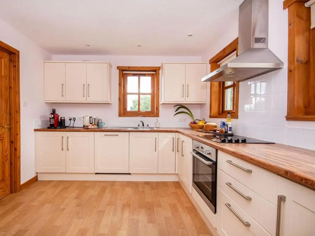 a kitchen with white cabinets and a stove top oven at Fernabeg in Edderton
