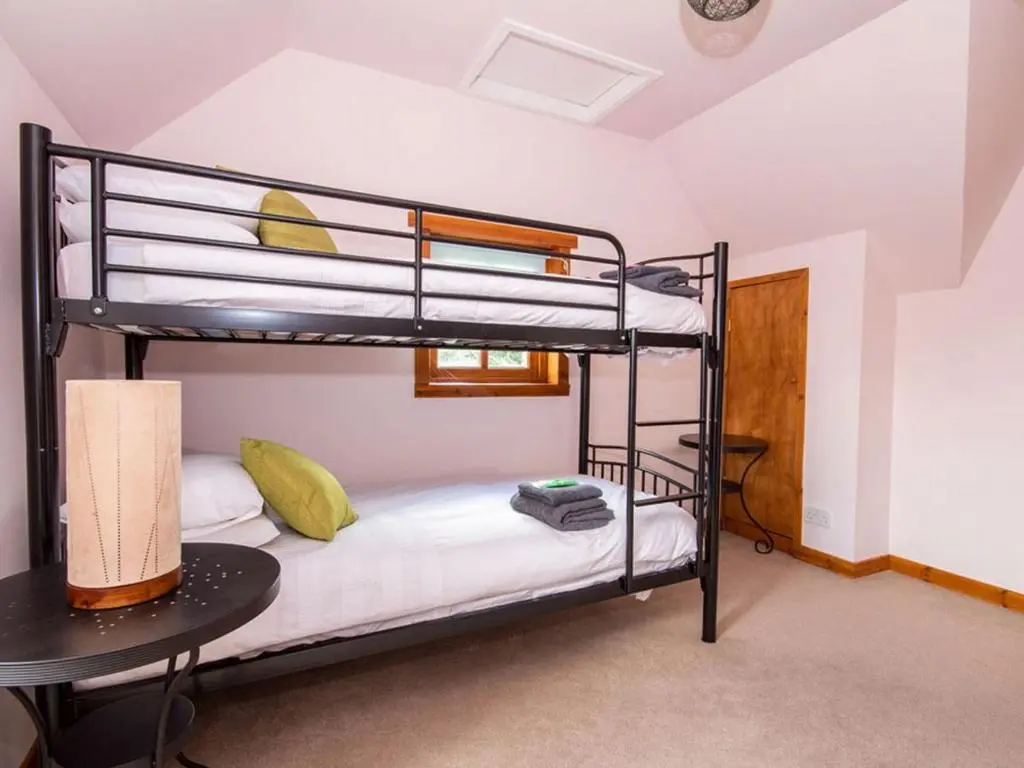 a bunk bed room with two bunk beds and a table at Fernabeg in Edderton