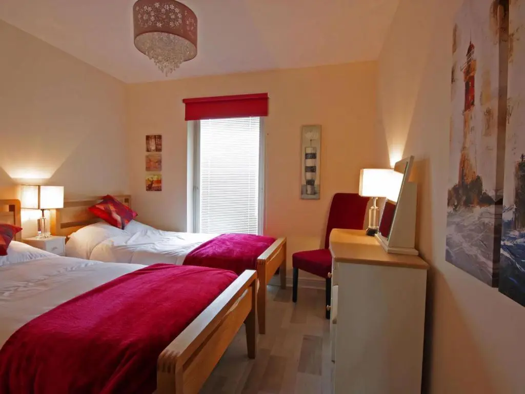 a hotel room with two beds and a chair at Fairway Apartment in Nairn