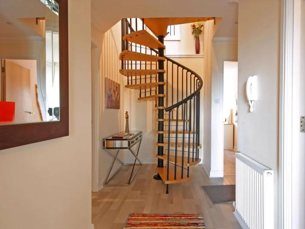 a hallway with a spiral staircase in a home at Fairway Apartment in Nairn