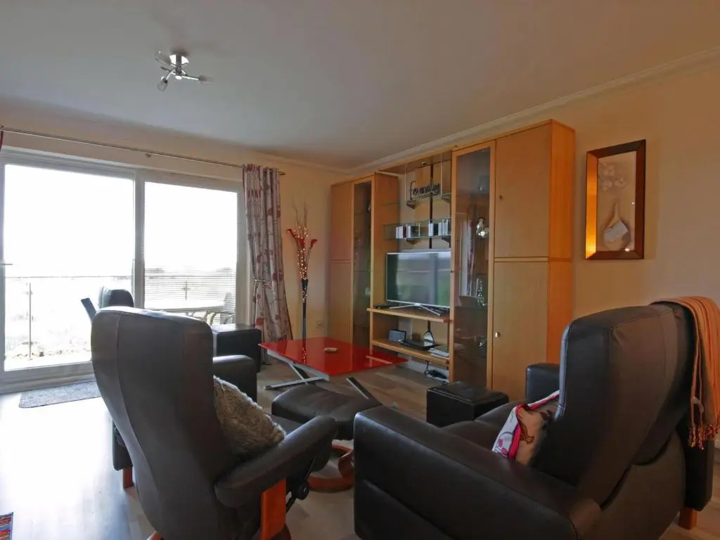 a living room with chairs and a child laying on a couch at Fairway Apartment in Nairn