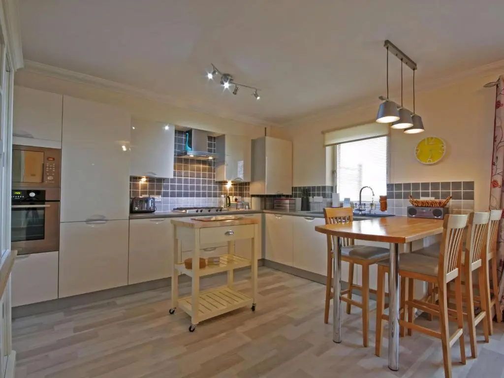 a kitchen with a wooden table and a wooden floor at Fairway Apartment in Nairn