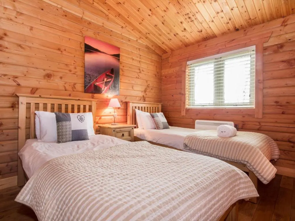 a bedroom with two beds in a log cabin at Gael Cham in Aviemore