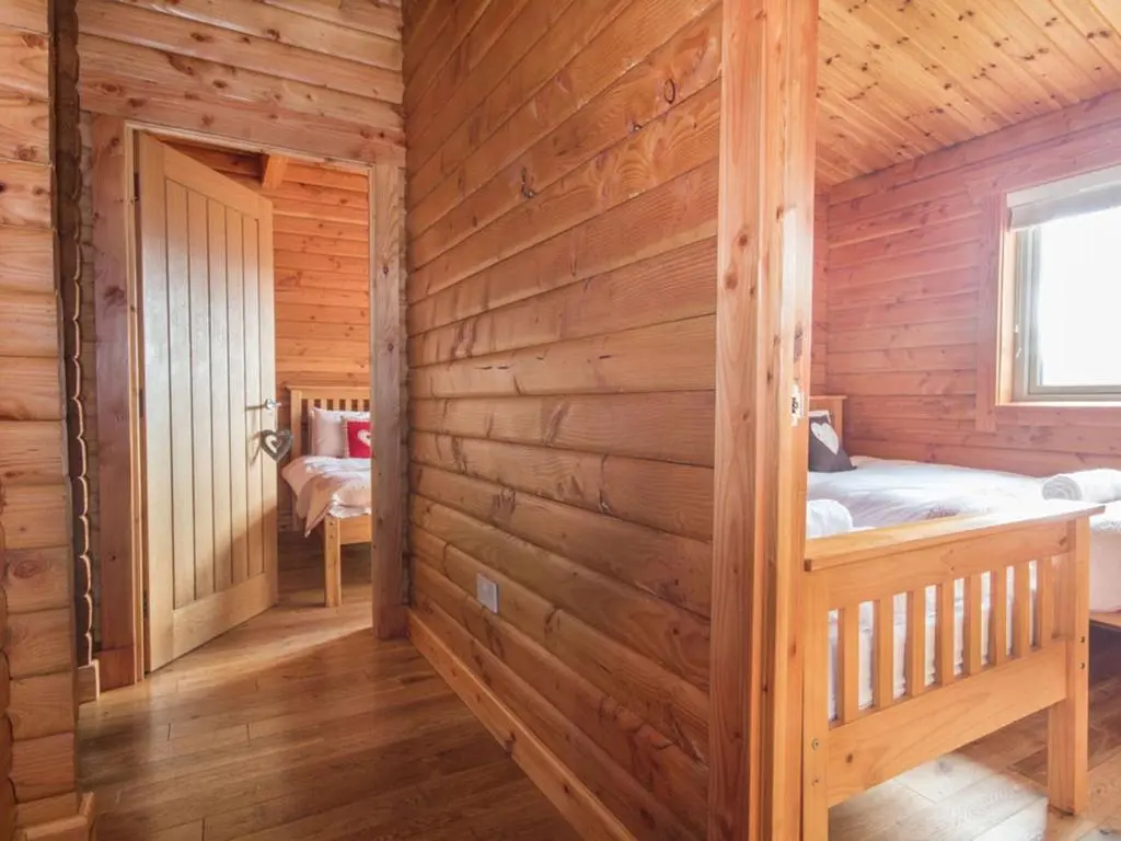 a log cabin with a bed and a window at Carn Eilrig in Aviemore