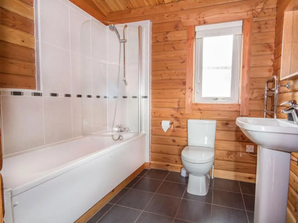 a bathroom with a tub and a toilet and a sink at Carn Eilrig in Aviemore