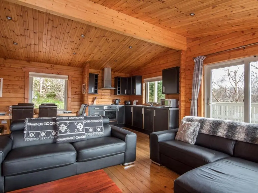 a living room with two couches and a kitchen at Carn Eilrig in Aviemore
