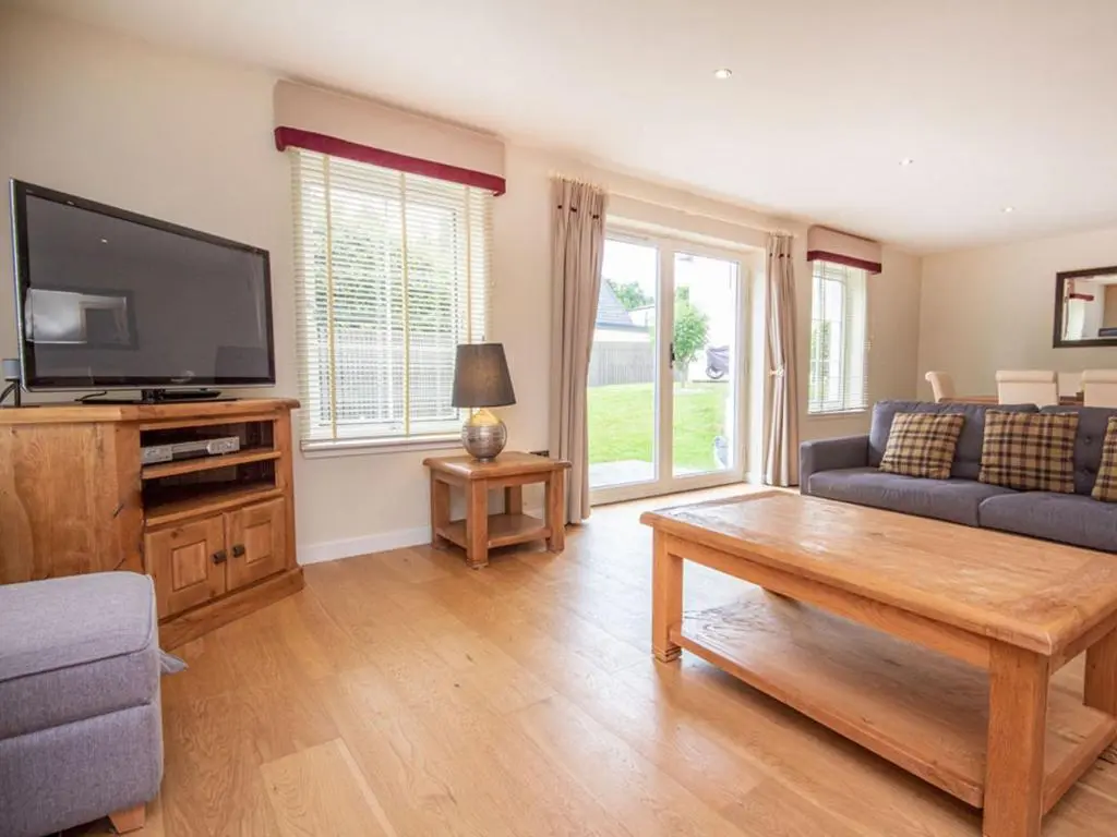 a living room with a couch and a tv at The Steading Apartment, No9 in Aviemore