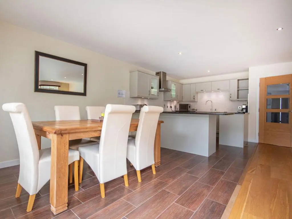 a kitchen and dining room with a wooden table and white chairs at The Steading Apartment, No9 in Aviemore