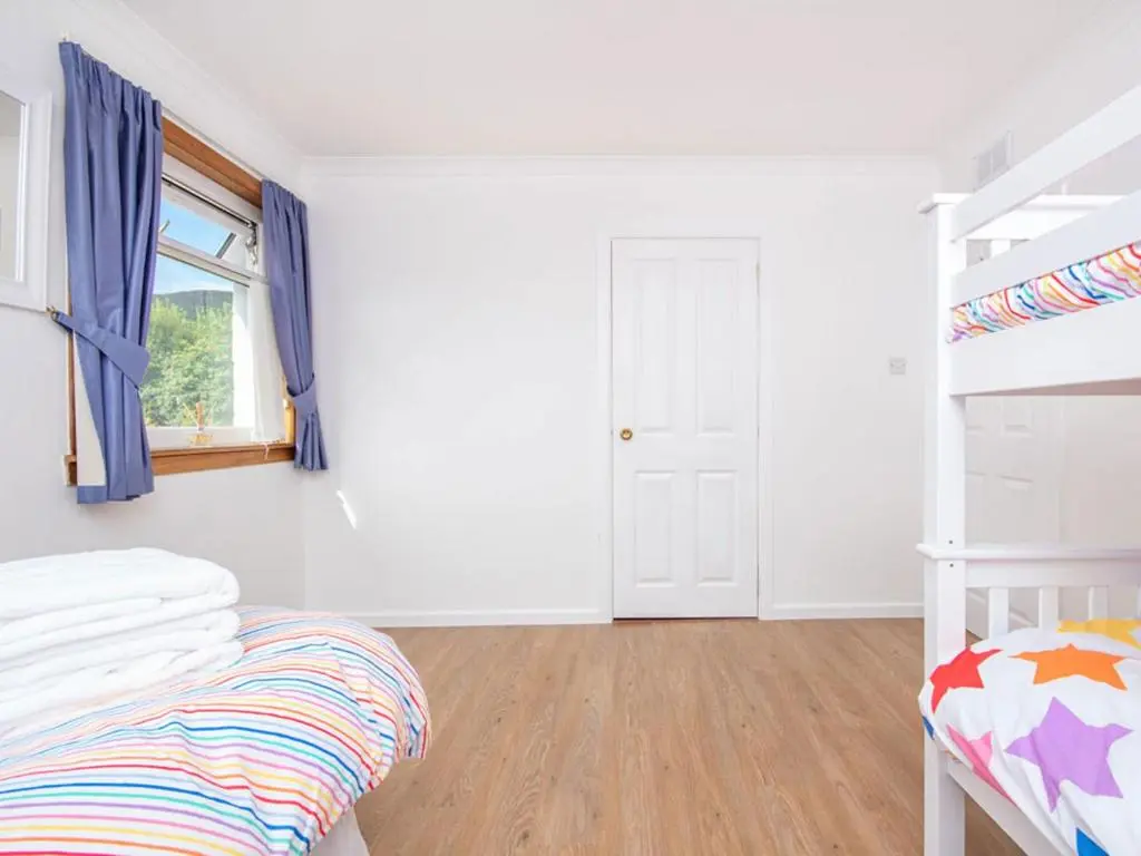 a white bedroom with a bunk bed and a window at Caledon in Aviemore