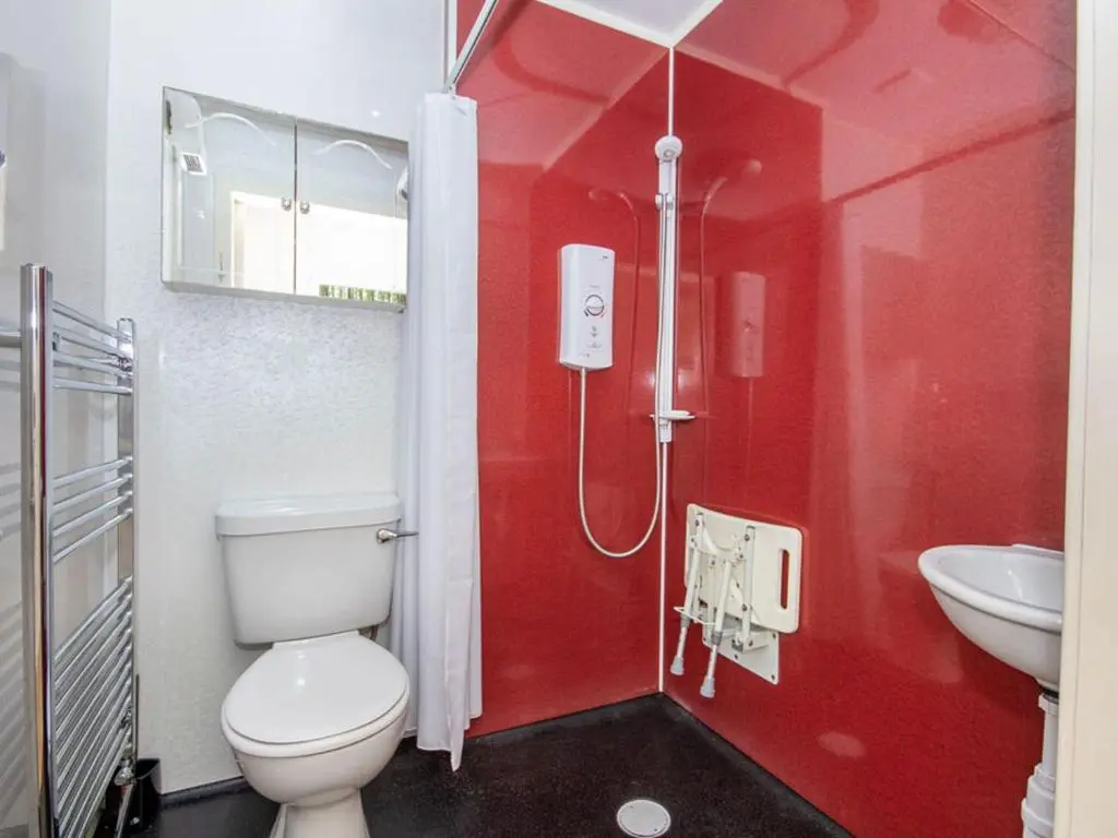 a red bathroom with a toilet and a sink at Caledon in Aviemore