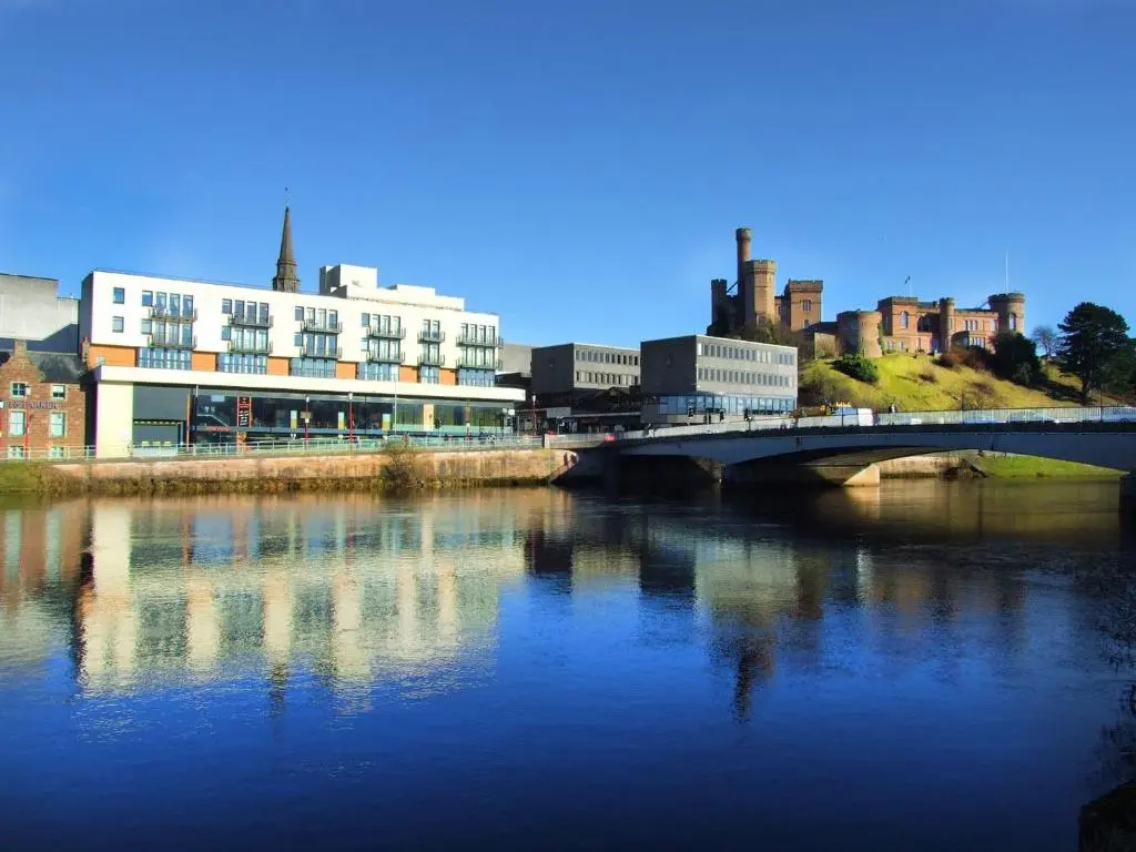 a bridge over a river in a city with buildings at 208 By The Bridge Apartment in Inverness