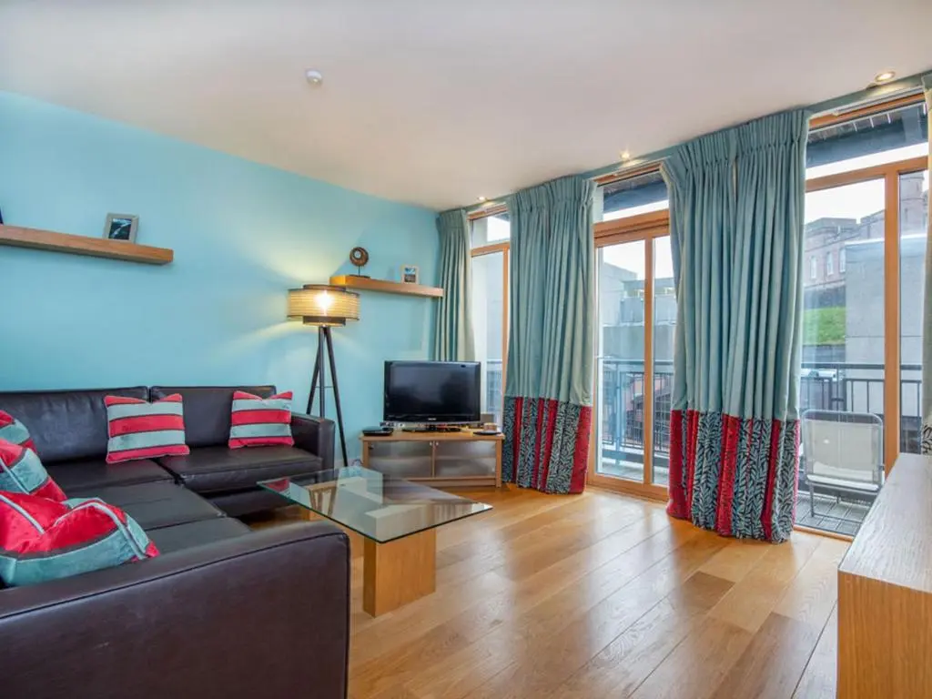 a living room with a couch and a tv at 208 By The Bridge Apartment in Inverness