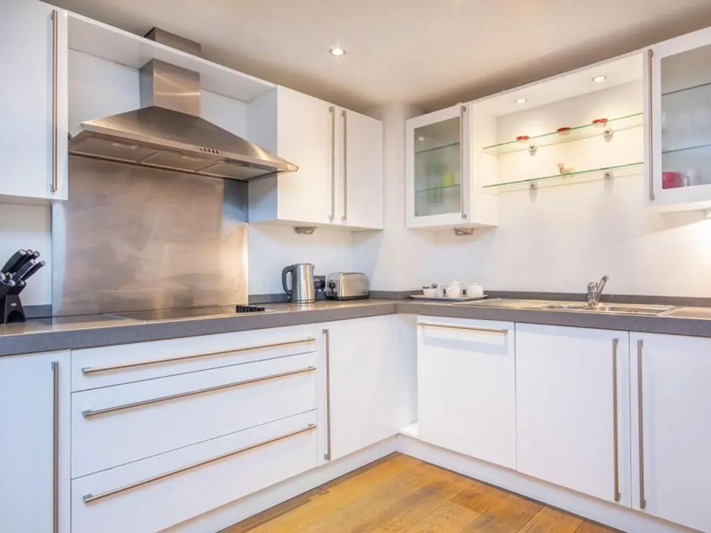 a kitchen with white cabinets and a sink at 208 By The Bridge Apartment in Inverness