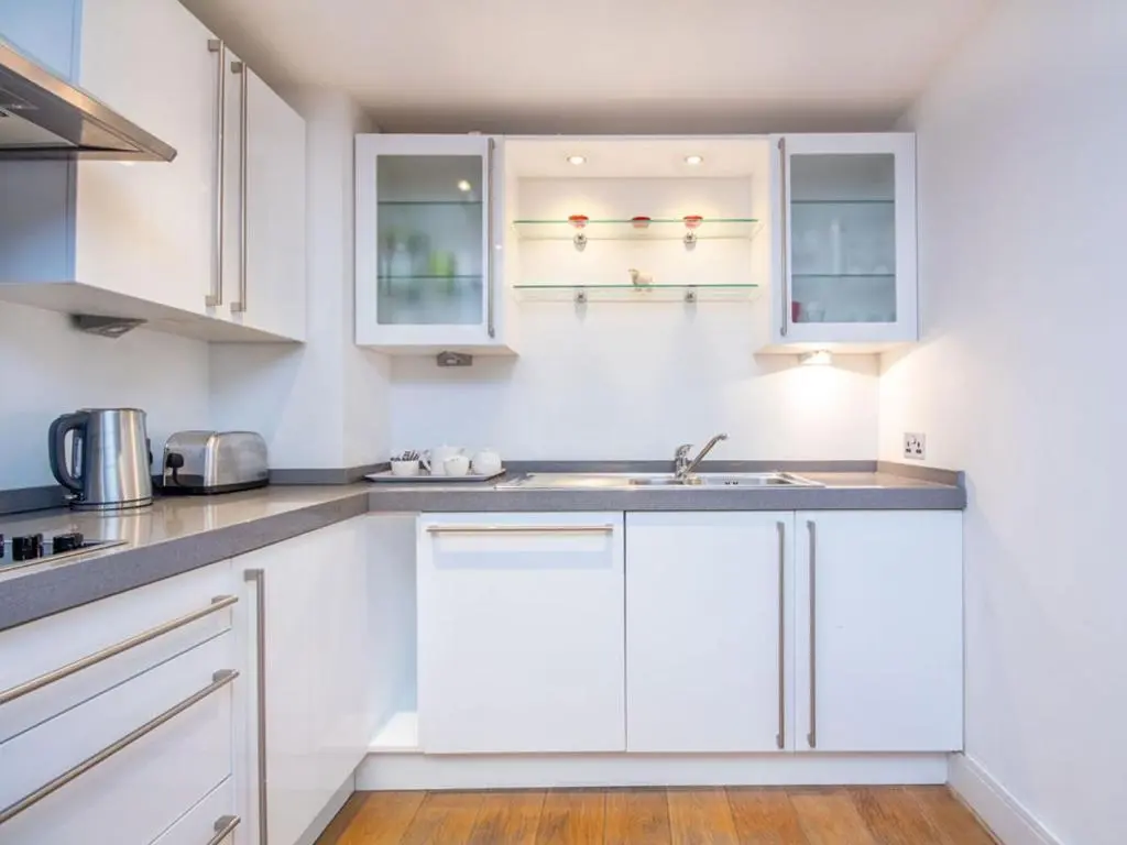a kitchen with white cabinets and a sink at 208 By The Bridge Apartment in Inverness