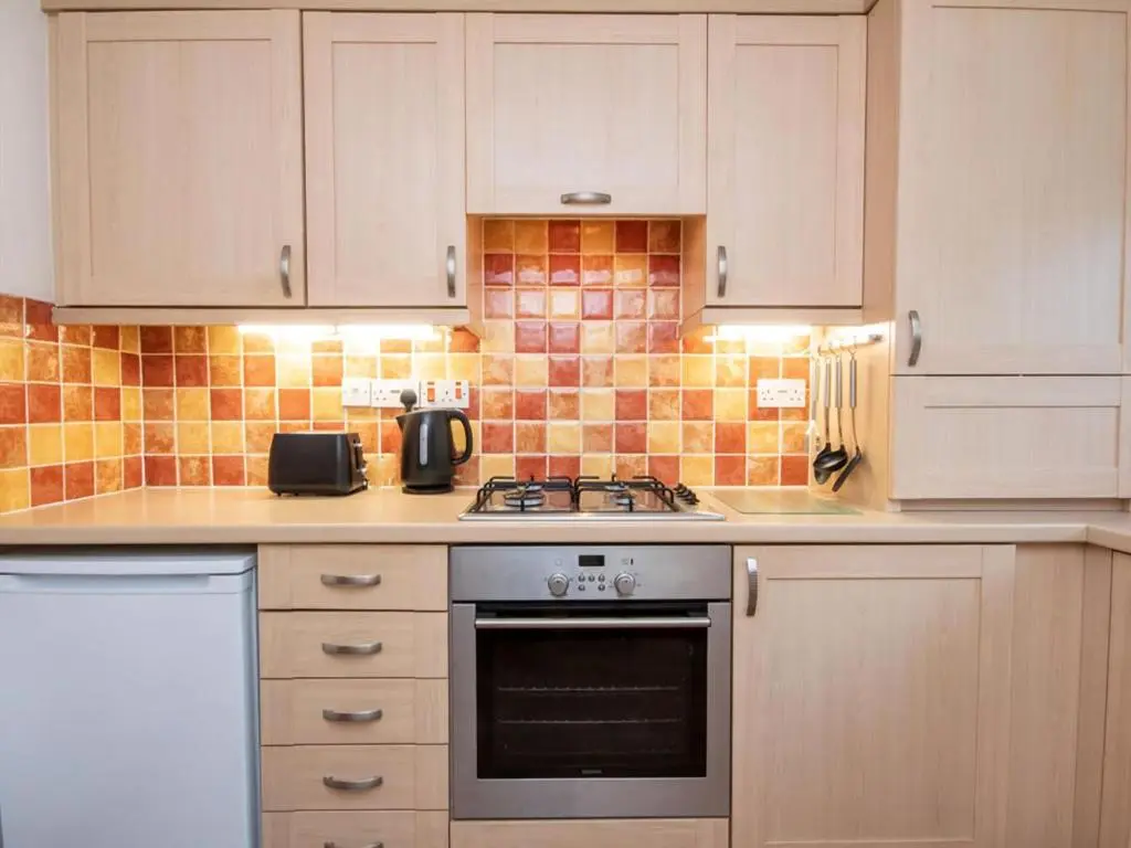 a kitchen with white cabinets and a stove top oven at Holm Dell Apartment in Inshes