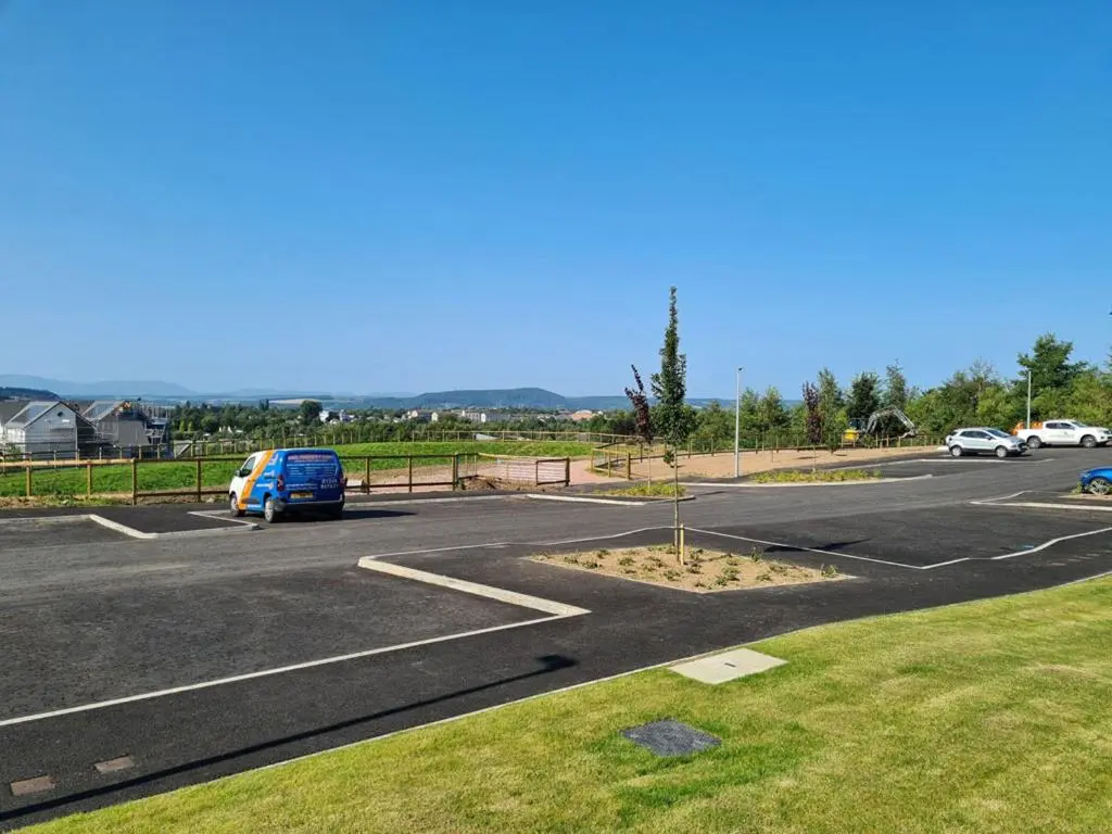 a parking lot with a blue van parked in it at Kessock View Apartment in Inshes
