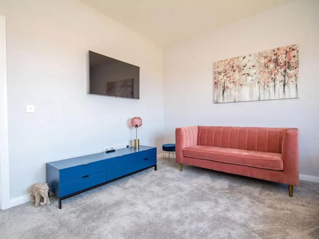 a living room with a red couch and a blue cabinet at Kessock View Apartment in Inshes
