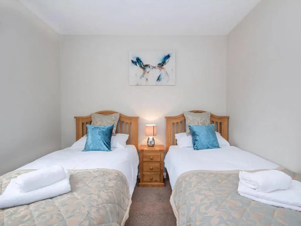 two twin beds in a bedroom with blue pillows at 58 Moray Park in Culloden