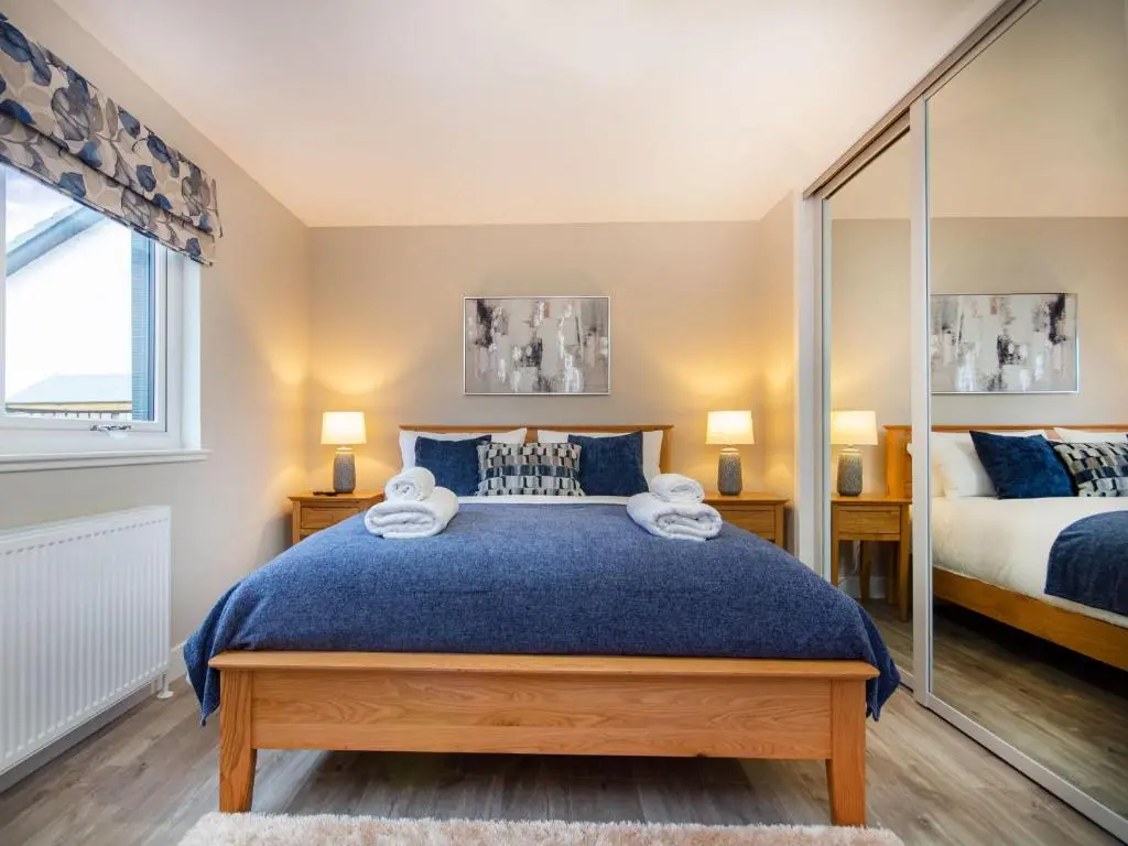 a bedroom with a large blue bed and a mirror at Sunnyside Culloden in Inverness