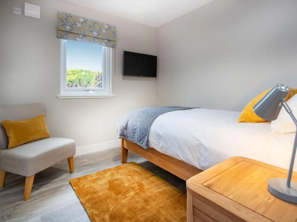 a bedroom with a bed and a chair and a window at Sunnyside Culloden in Inverness