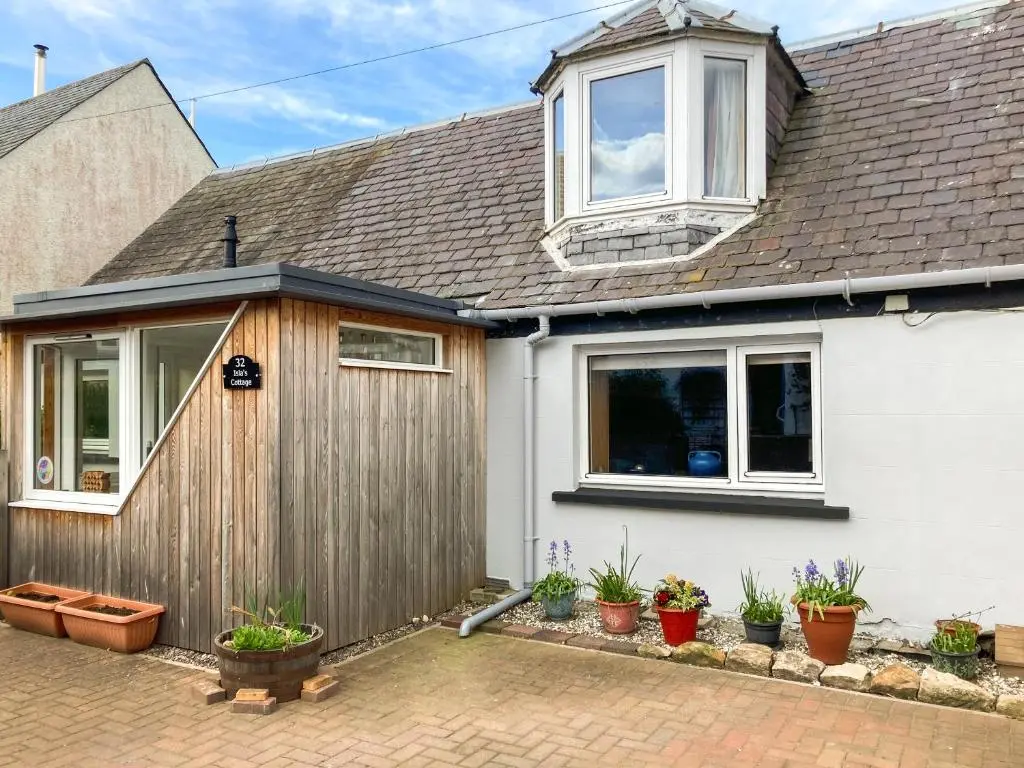 a white house with windows and potted plants at Isla's Cottage in Nairn