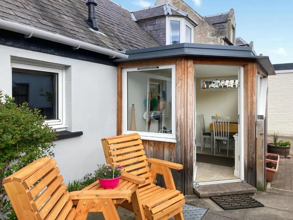 two wooden chairs sitting outside of a house at Isla's Cottage in Nairn