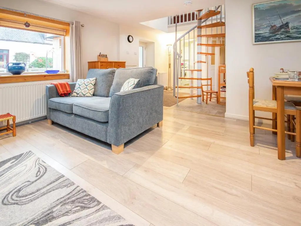 a living room with a blue couch and wooden floors at Isla's Cottage in Nairn