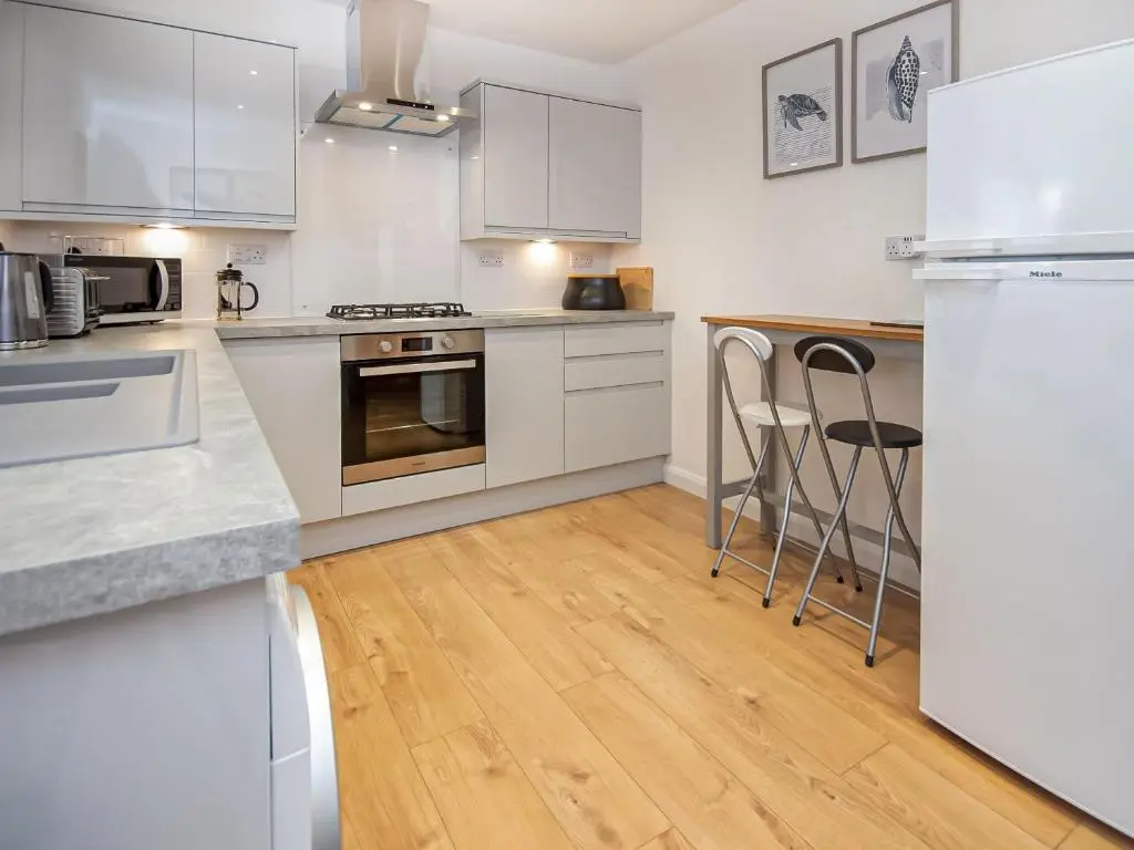 a kitchen with white appliances and a wooden floor at Bow Fiddle in Nairn