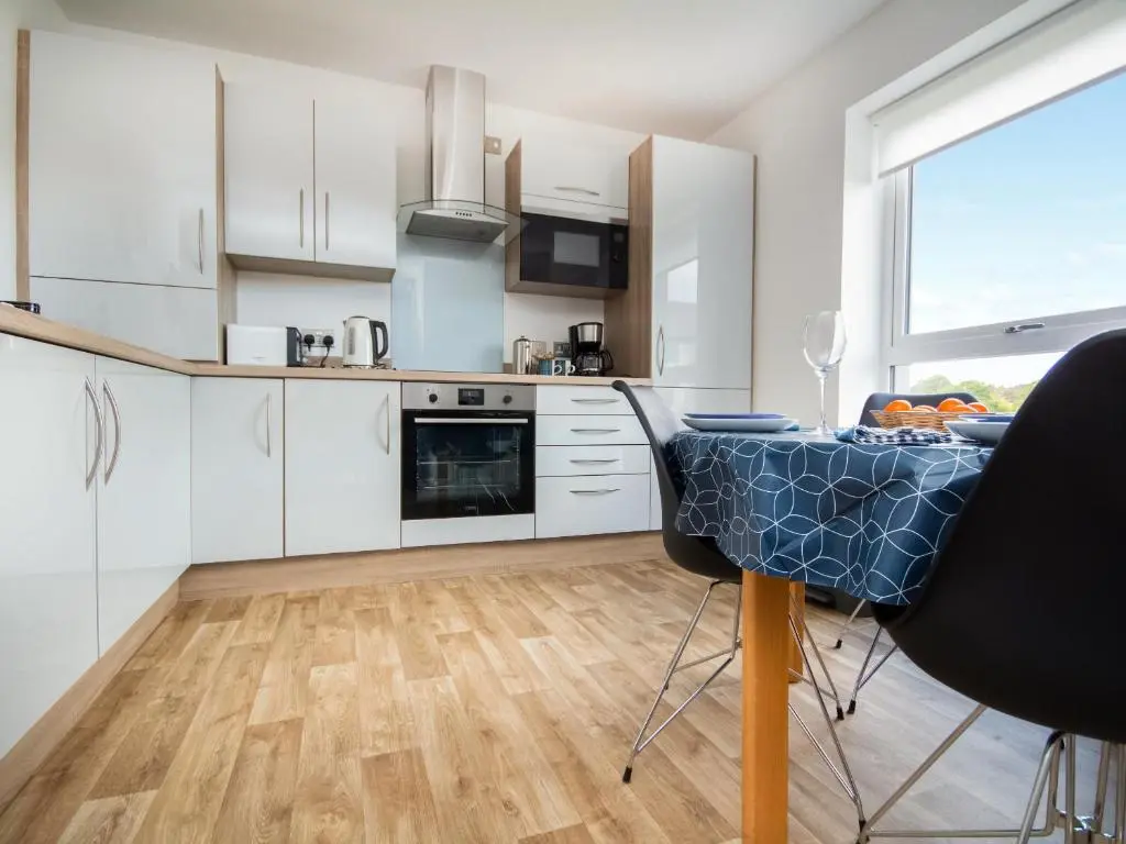 a kitchen with white cabinets and a table with chairs at Thistledown in Dornoch