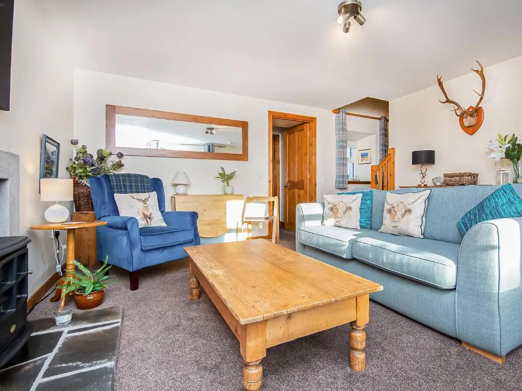 a living room with two blue couches and a coffee table at Sunnyside Cottage in Embo