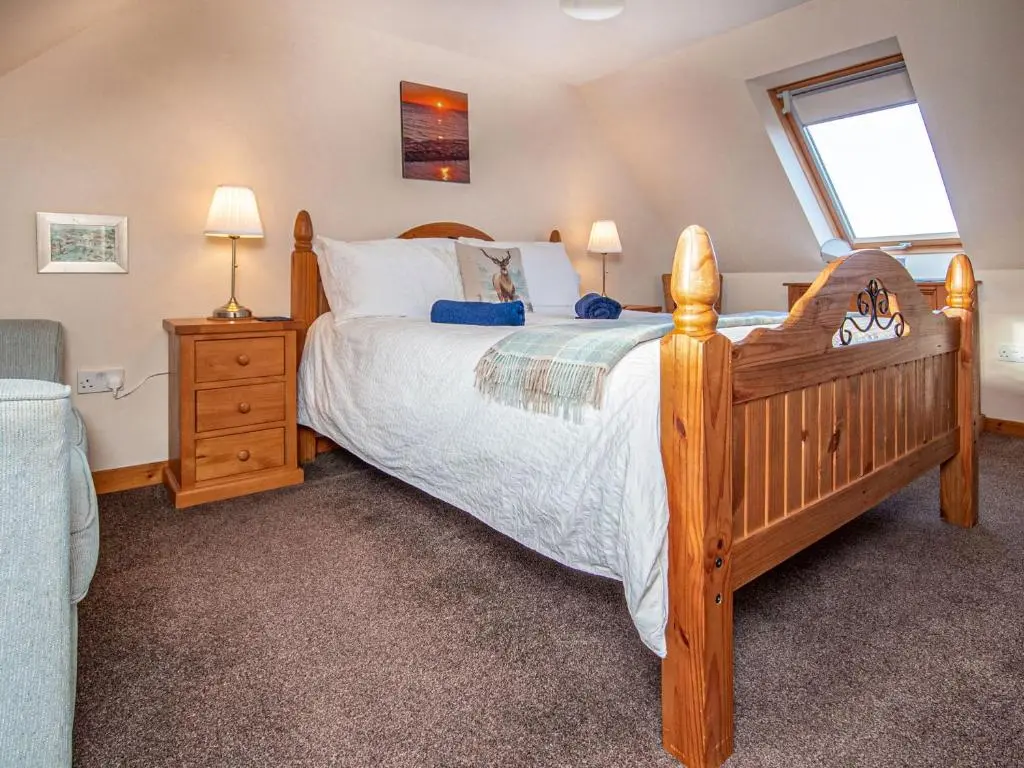 a bedroom with a large wooden bed and a window at Sunnyside Cottage in Embo