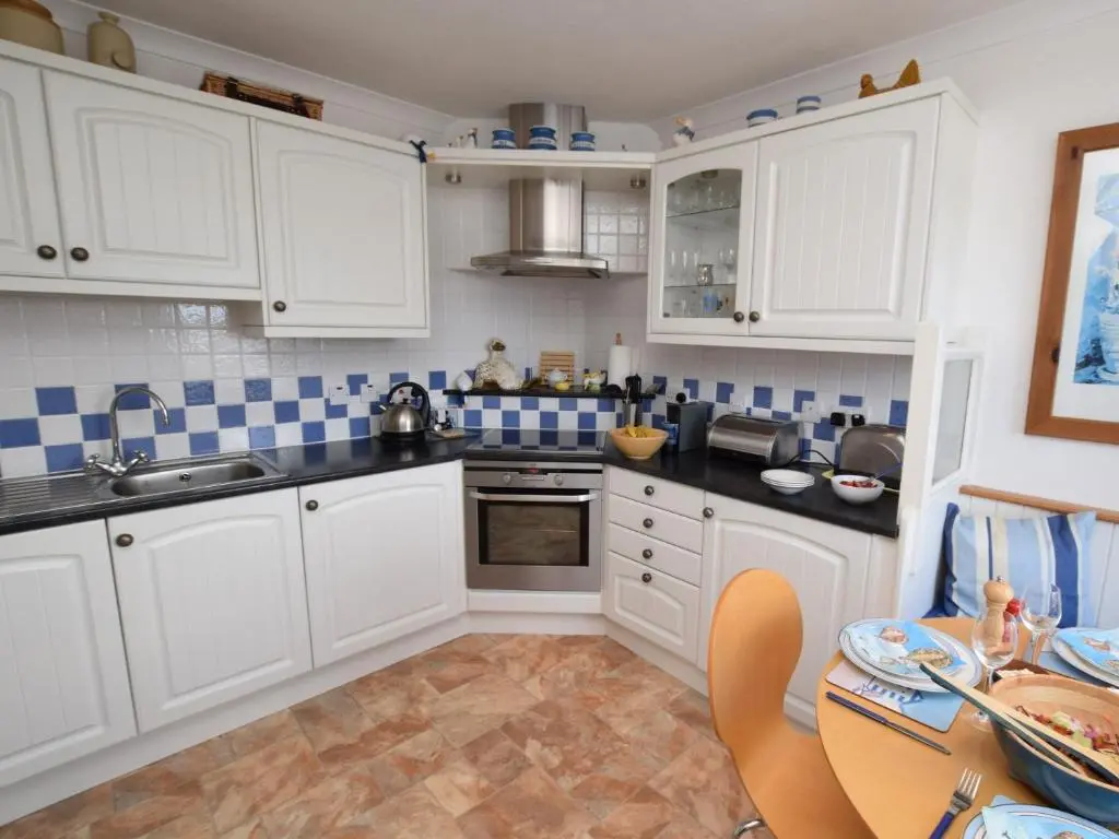 a kitchen with white cabinets and blue and white tiles at 2 Bed in Findochty 76557 in Findochty