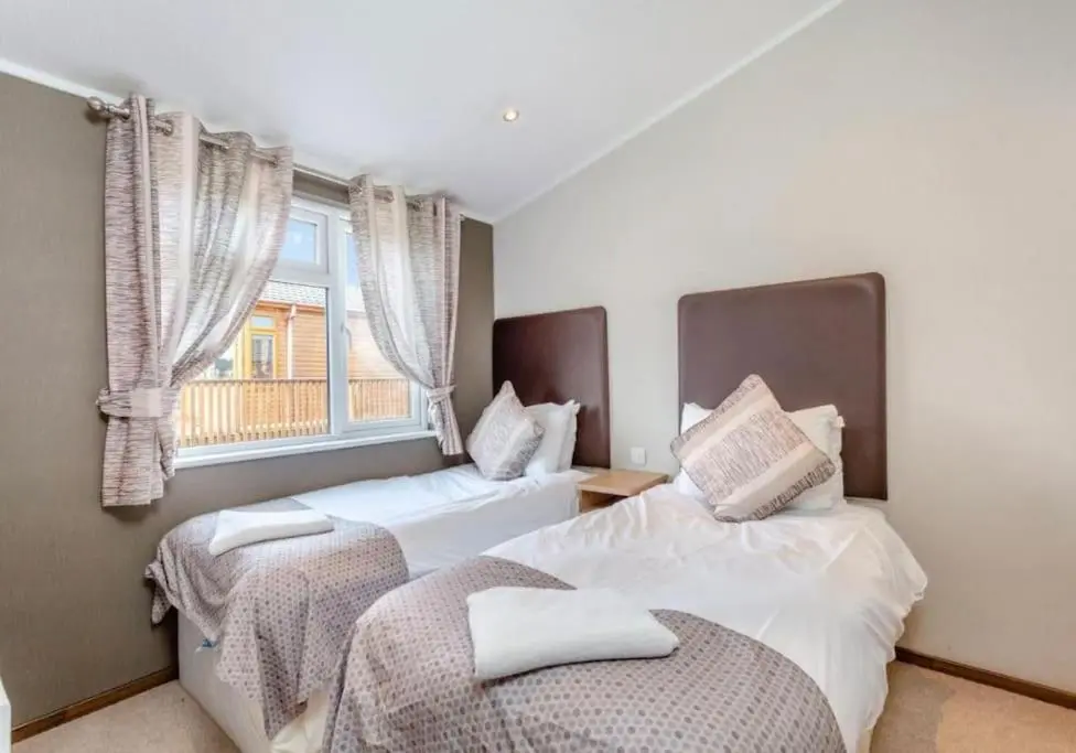 two beds in a room with a window at Scottish retreat in Banchory