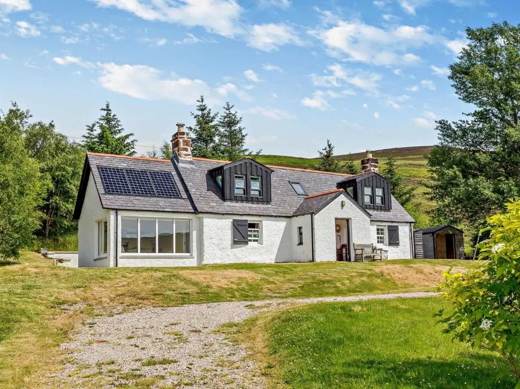 a white house with solar panels on the roof at 3 Bed in Kildonan SU192 in Helmsdale