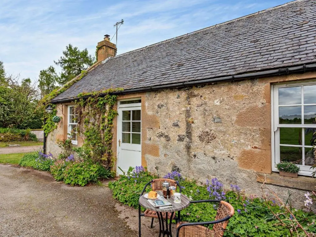 a stone cottage with a table and chairs in front of it at 2 Bed in Conon Bridge CA387 in Cononbridge
