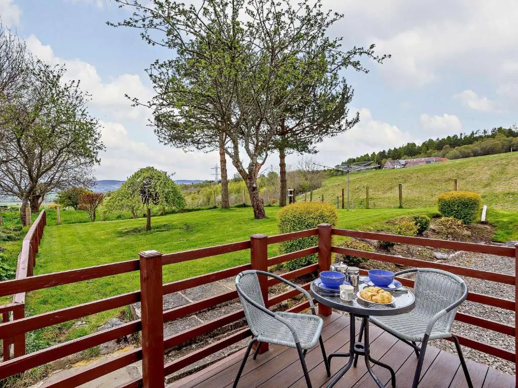 a table and two chairs on a wooden deck at 1 Bed in Beauly 82778 in Beauly