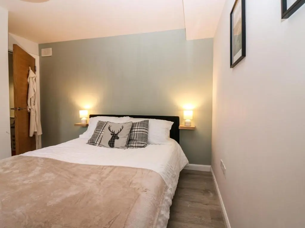 a small bedroom with a bed with two lamps at 11 Ambleside Court in Banchory