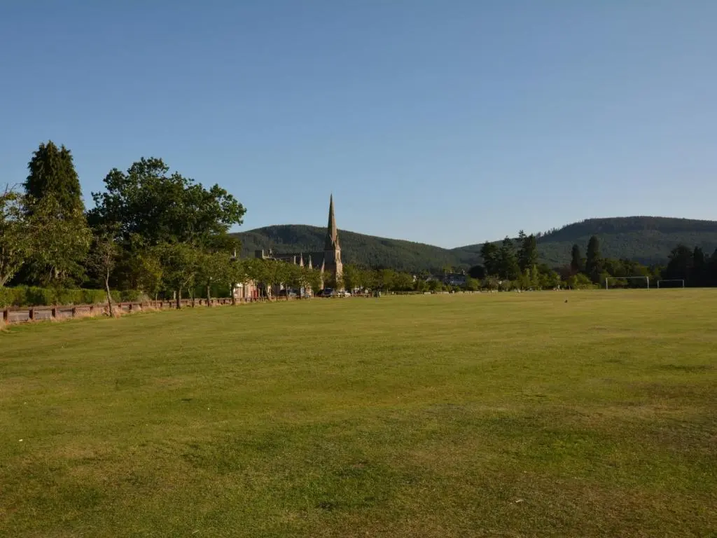 a large grass field with a church in the distance at 3 Bed in Dinnet 53150 in Dinnet