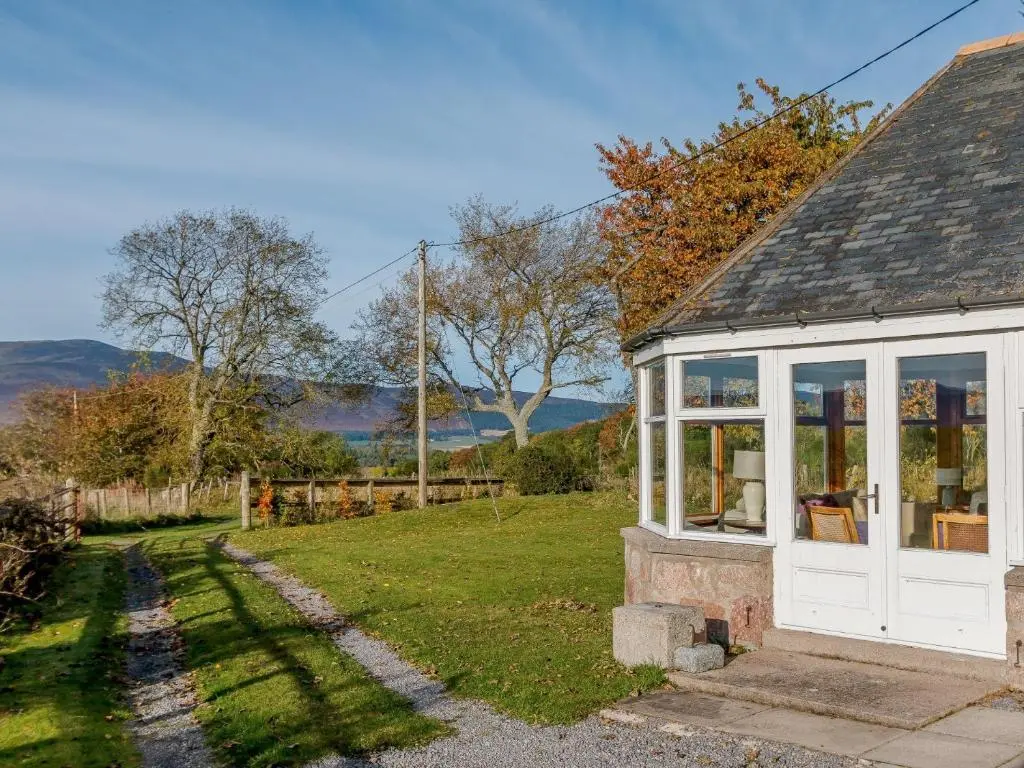 a small cottage with a white door and windows at 3 Bed in Dinnet 53150 in Dinnet