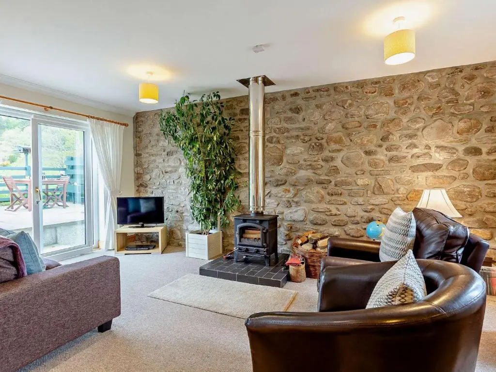 a living room with a stone wall with a stove at 1 Bed in Beauly 82779 in Beauly
