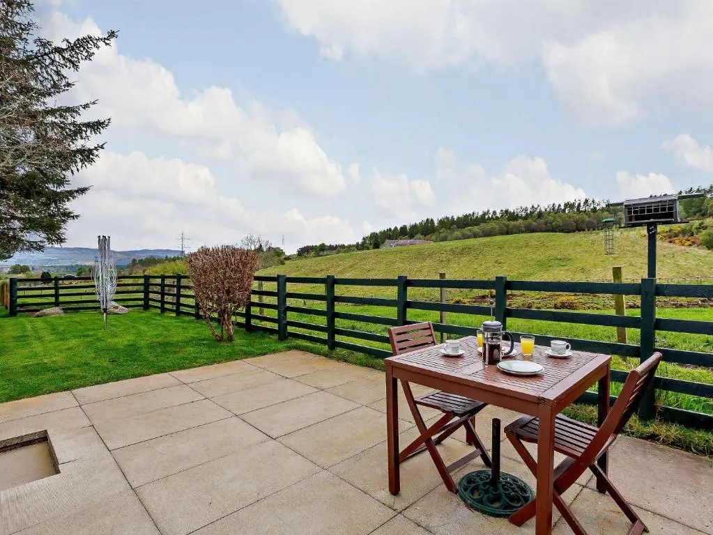 a table and chairs on a patio with a fence at 1 Bed in Beauly 82779 in Beauly