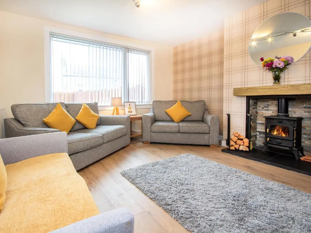 a living room with two couches and a fireplace at Colbheinn Cottage in Brora