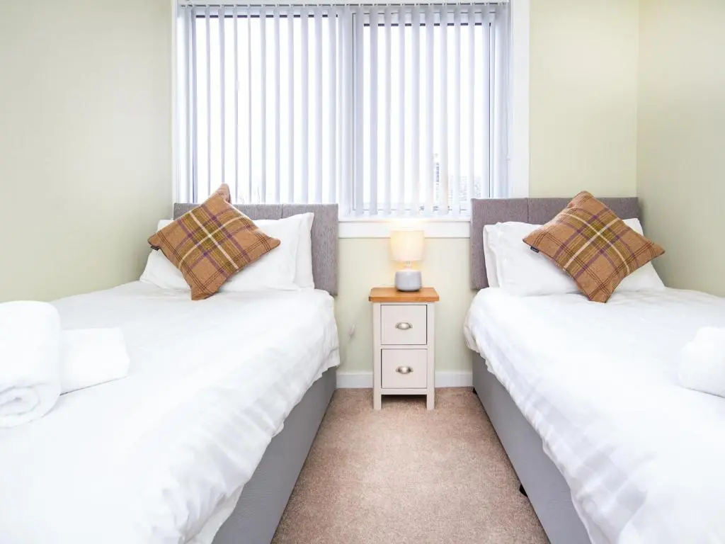 two twin beds in a room with a window at Colbheinn Cottage in Brora