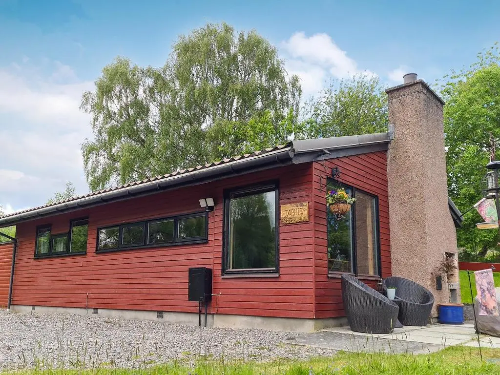 a small red building with a tree in the background at Dornie Lodge in Beauly