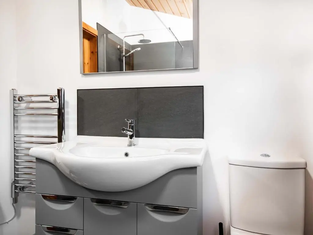 a bathroom with a white sink and a mirror at Dornie Lodge in Beauly