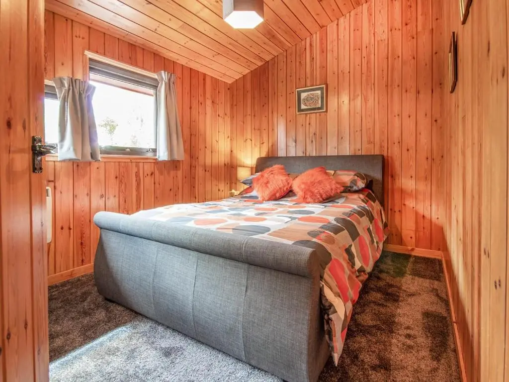 a bedroom with a bed in a wooden wall at Dornie Lodge in Beauly
