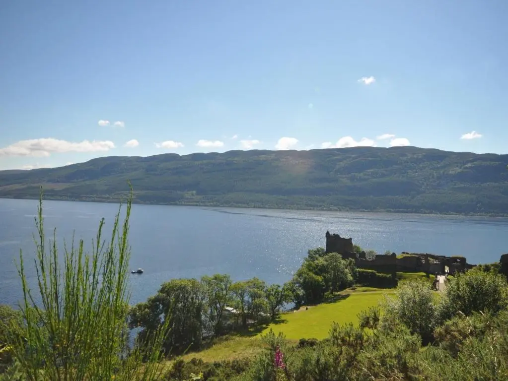 a castle sitting on the shore of a lake at 3 Bed in Drumnadrochit IN633 in Balnain
